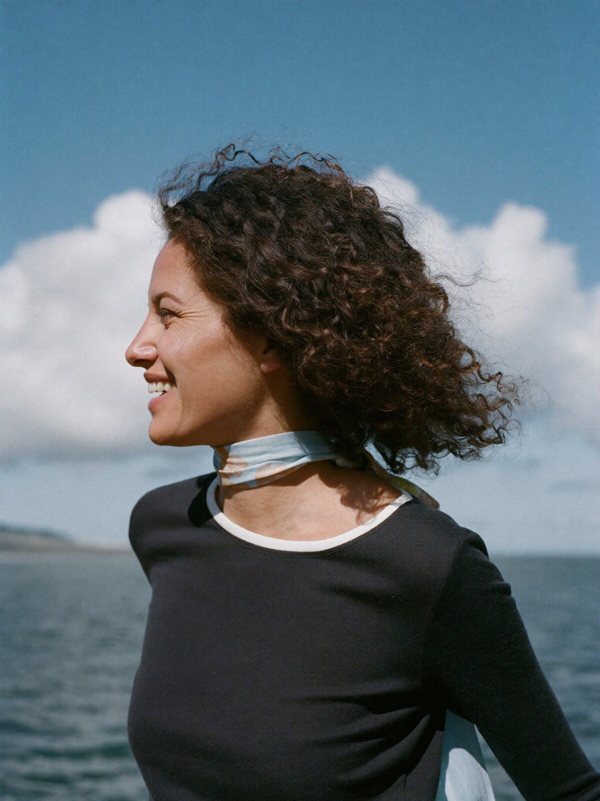 A woman laughing as she looks out to sea from a coastal path